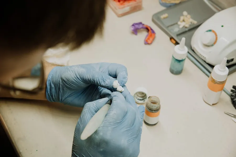 Dental laboratory technician crafting a high-quality prosthetic restoration — quality materials and skilled lab work underpin safe, durable dental treatment